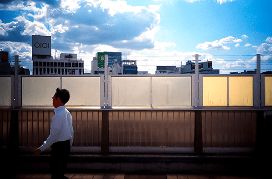 Man walking over a bridge in sunshine